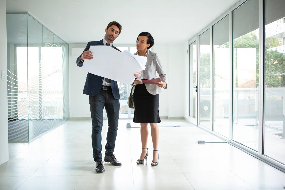 A commercial real estate broker walking a prospective tenant through a vacant office floor