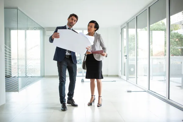 A commercial real estate broker walking a prospective tenant through a vacant office floor