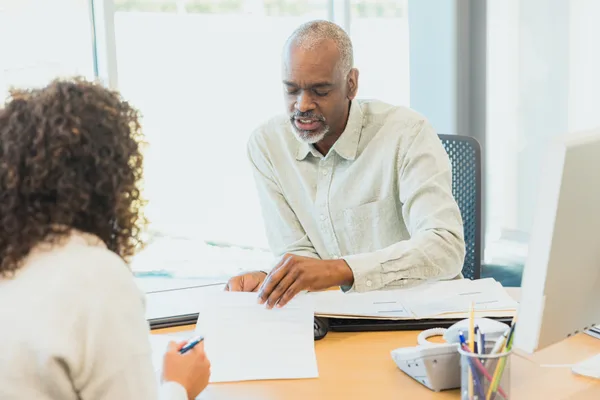 A credit repair specialist reviewing a credit report and dispute paperwork with a client across a desk