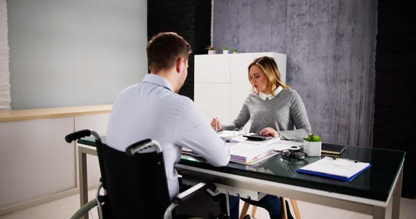 A Social Security disability attorney reviewing claim paperwork with a client across a desk