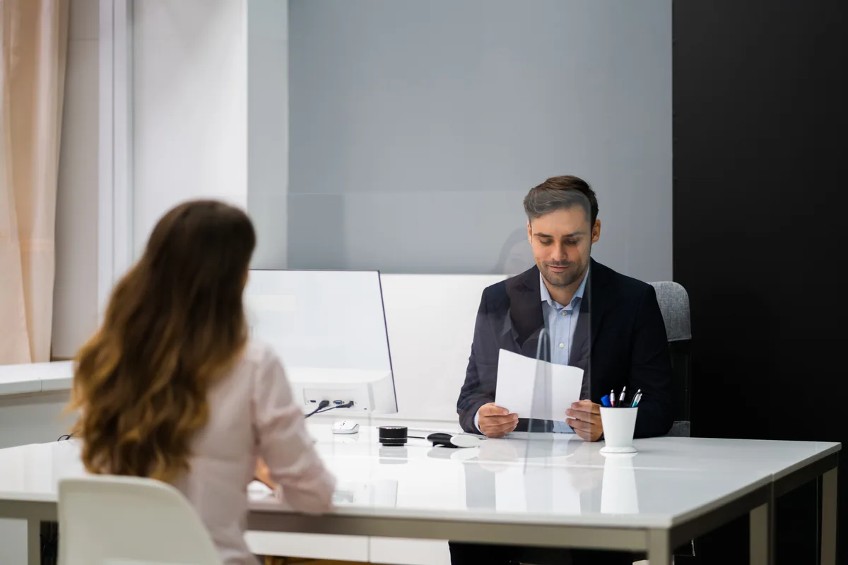 An employment lawyer reviewing termination paperwork with a client across a desk in a law office