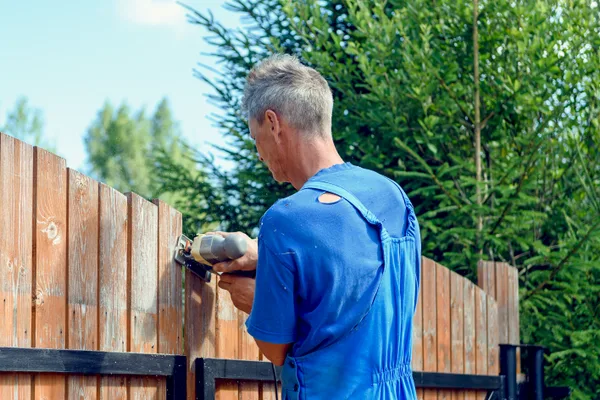 Fence contractor installing a cedar privacy fence panel in a suburban backyard on a clear day
