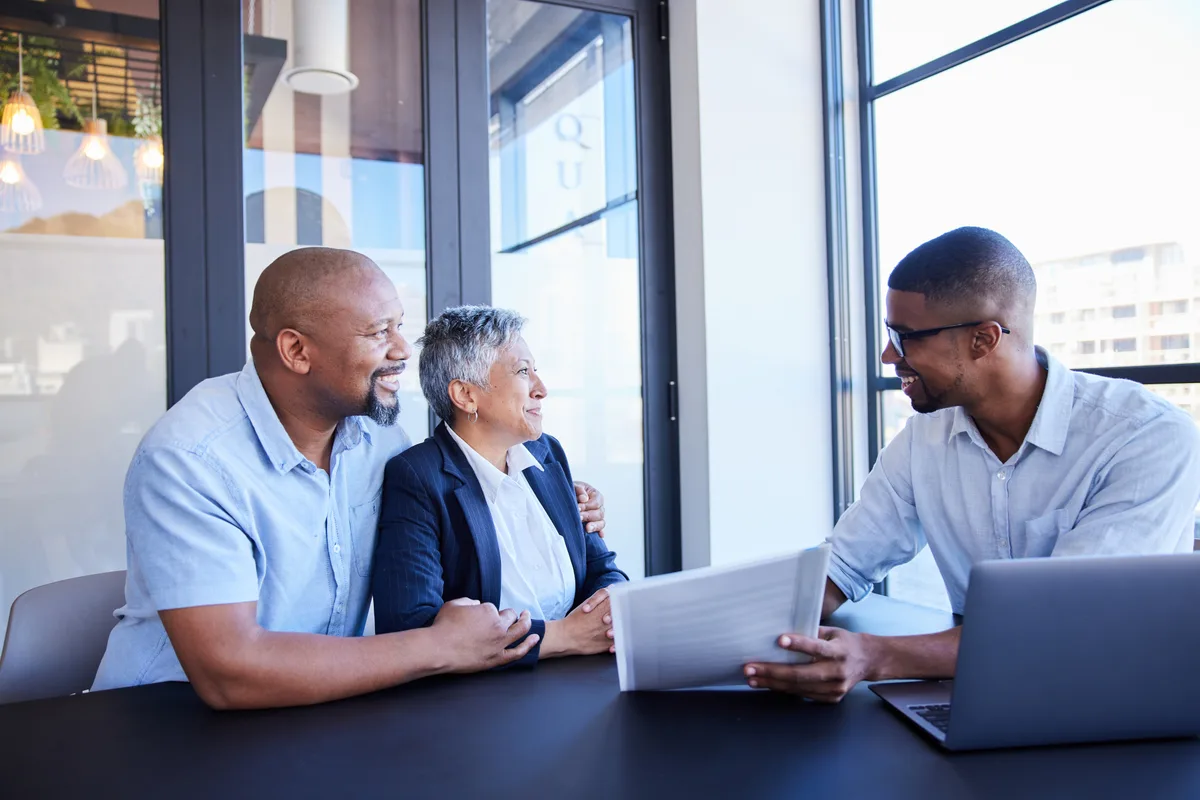 A financial advisor walking a couple through a retirement plan at a conference table in a bright office