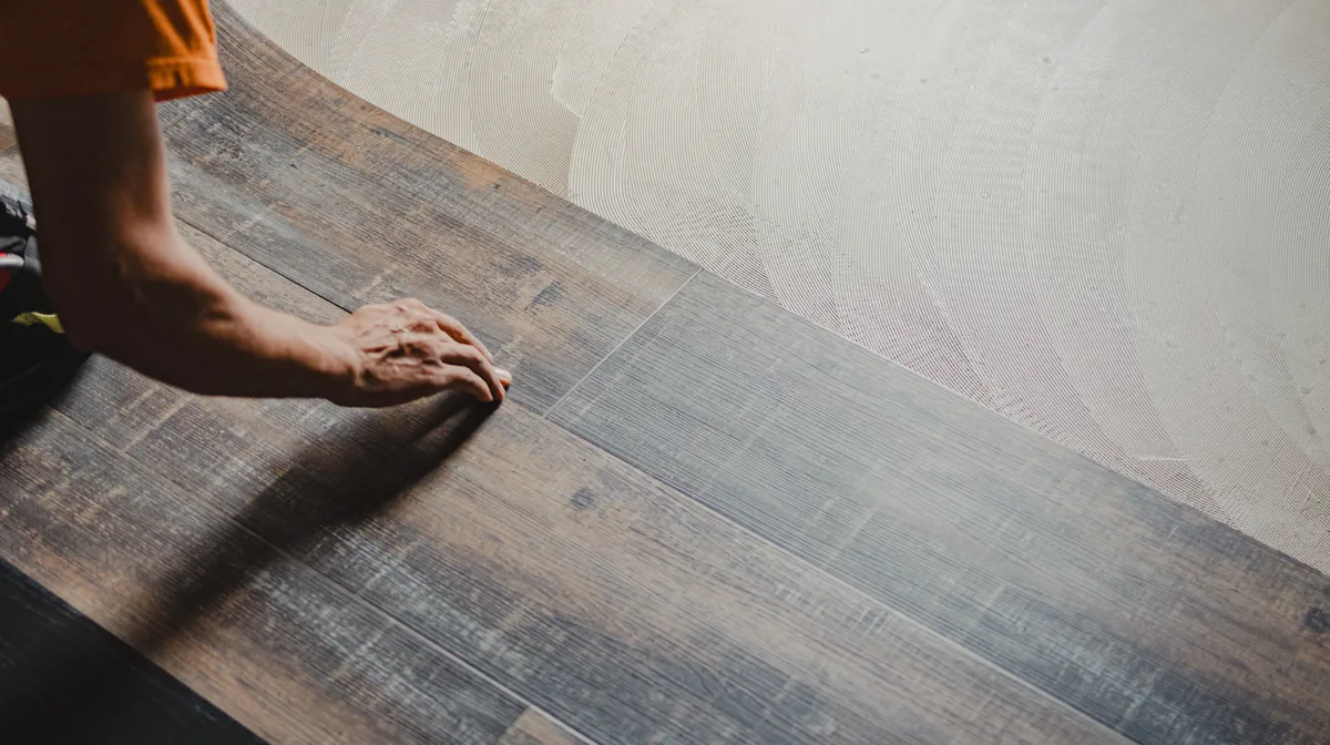Flooring installer fitting luxury vinyl plank in a bright residential room