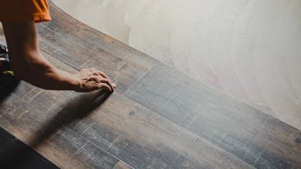 Flooring installer fitting luxury vinyl plank in a bright residential room