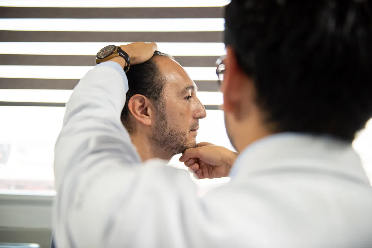 Hair restoration surgeon reviewing a patient's hairline during a clinic consultation