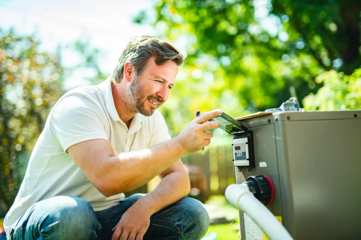 Technician servicing the heater panel of a backyard hot tub while the owner looks on