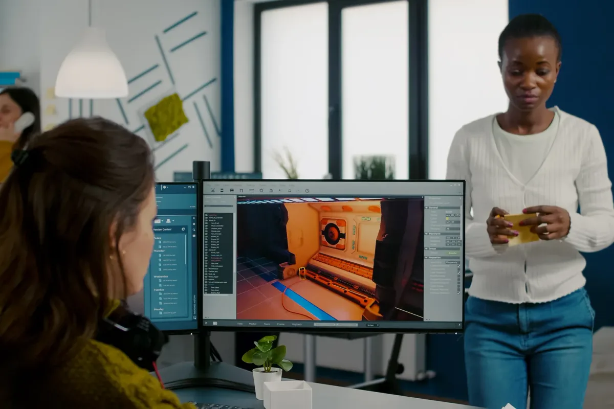 Game studio developers reviewing a mobile prototype and retention charts together at a monitor