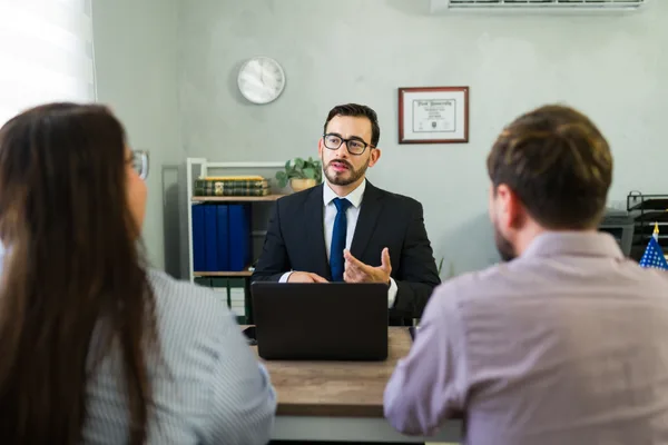 Immigration attorney reviewing case documents with a couple across a desk in a bright office