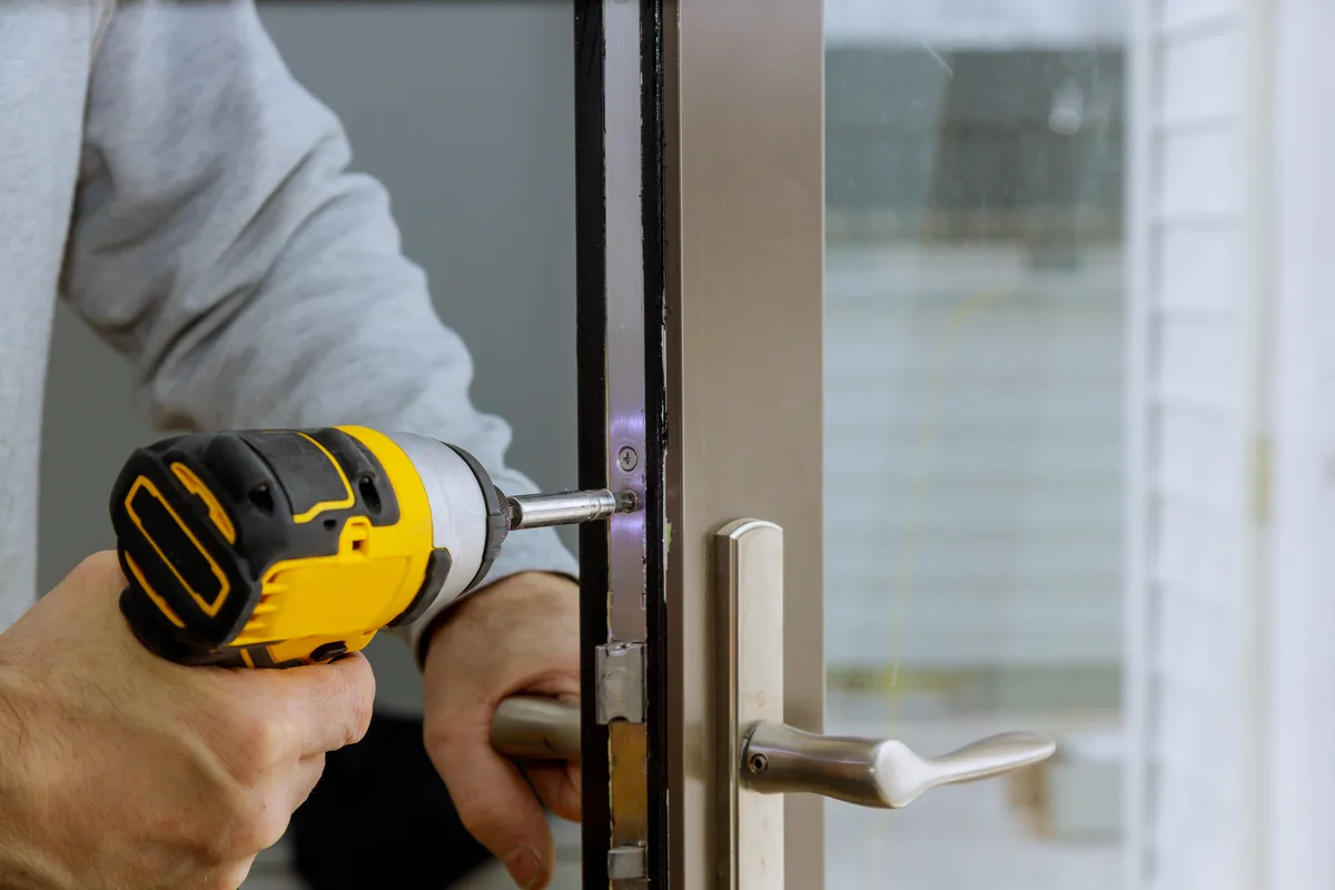 A locksmith installing a deadbolt on a residential front door during a service call