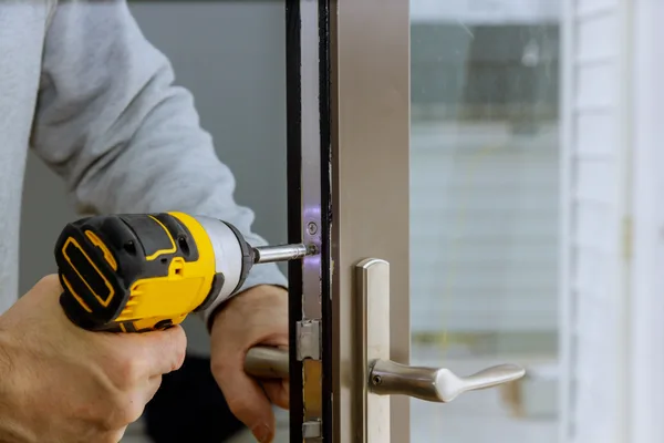 A locksmith installing a deadbolt on a residential front door during a service call