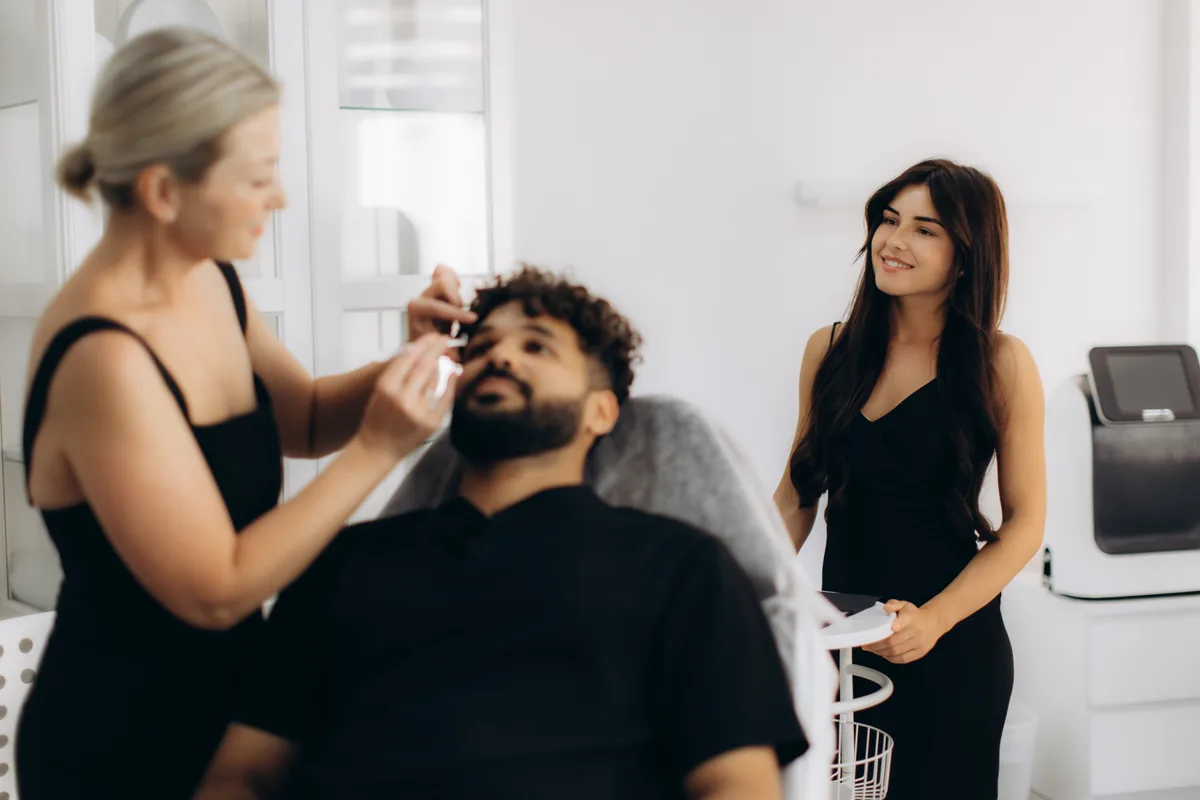 Permanent makeup artist microblading a client's eyebrows in a bright modern studio
