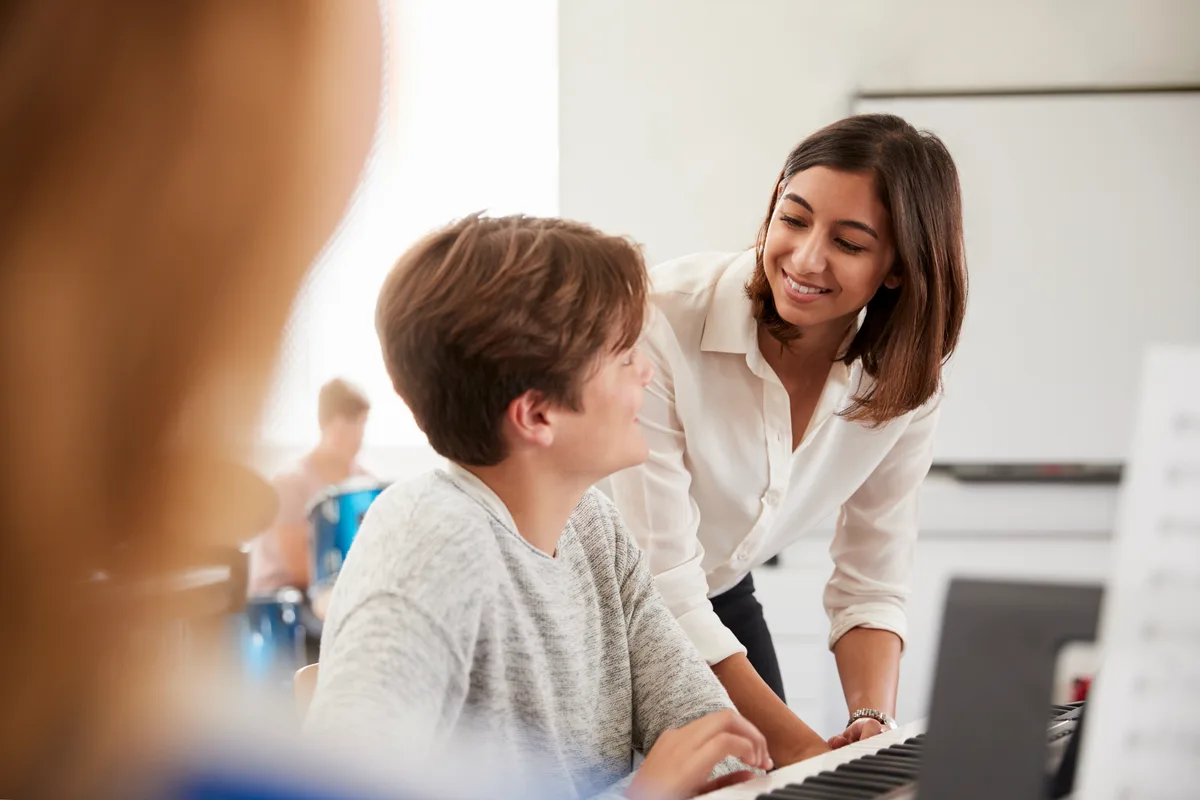A music teacher guiding a young student through a piano lesson in a studio