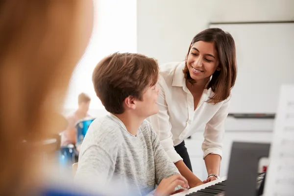A music teacher guiding a young student through a piano lesson in a studio