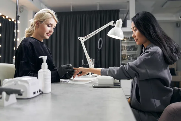 Nail technician applying gel polish at a manicure station in a modern nail salon
