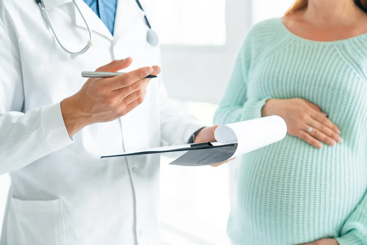 An OB/GYN physician reviewing care options with a patient at a desk in a bright, modern women's health clinic