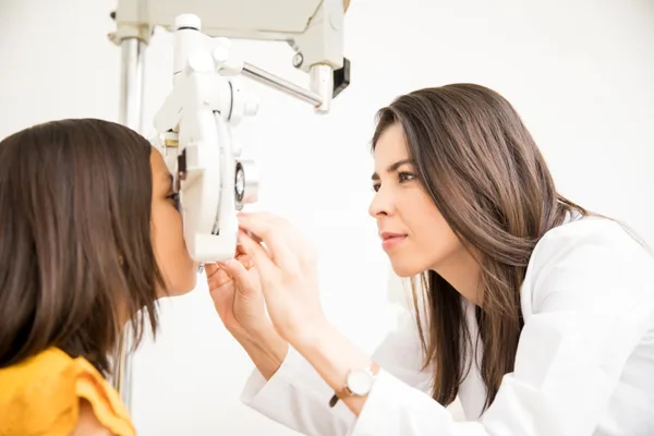 Optometrist performing a comprehensive eye exam on a patient in a bright modern clinic