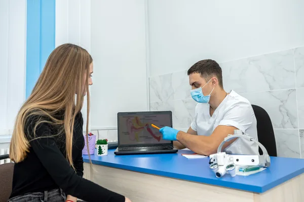 An oral and maxillofacial surgeon reviewing a dental implant treatment plan with a patient at a chairside monitor