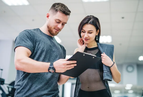 Personal trainer reviewing a training program with a client during a one-on-one session in a bright gym