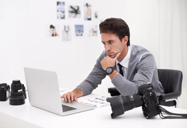 A photographer reviewing edited images and inquiry messages on a laptop in a bright studio