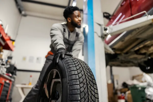 Tire technician mounting a new tire on a wheel inside a modern shop bay