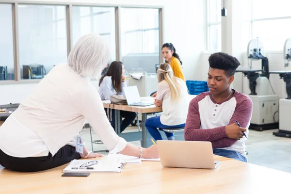 A tutor and a high-school student reviewing test-prep material together at a table in a learning center