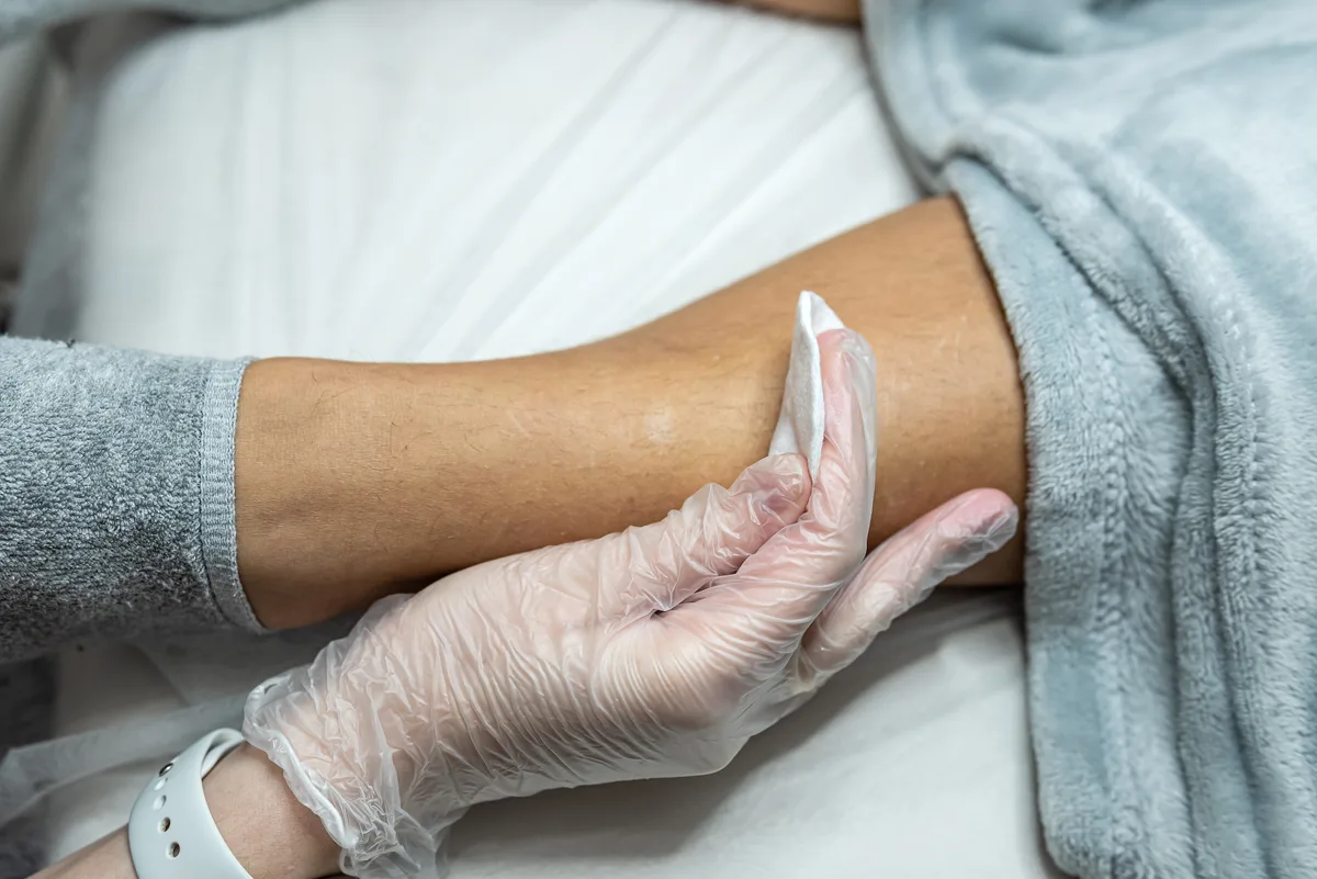 Esthetician applying wax to a client's leg in a clean, modern studio treatment room