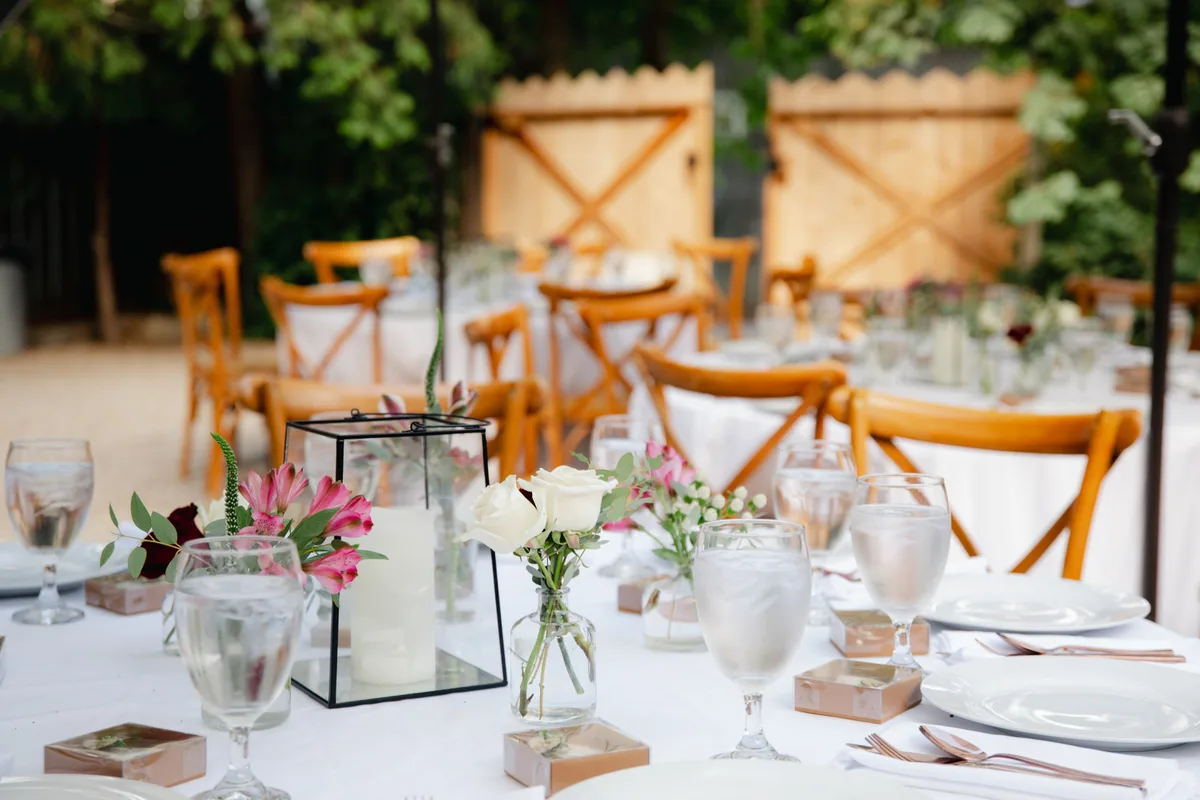 An elegant wedding reception venue set with round tables, florals and warm lighting before an event