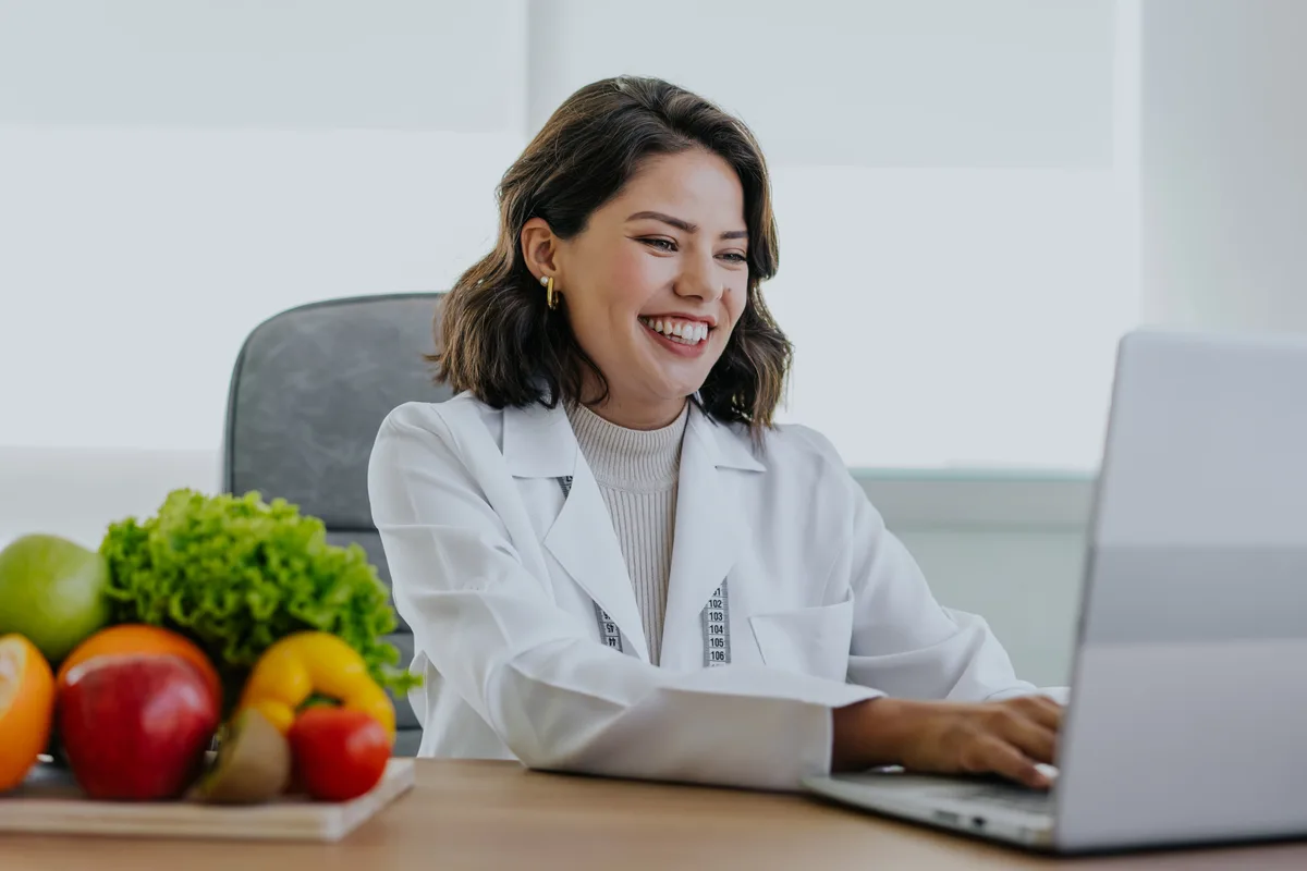 A clinician reviewing a medical weight-loss plan with a patient across a desk in a bright clinic consultation room