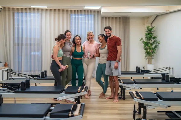 Instructor guiding a group reformer pilates class in a bright boutique studio