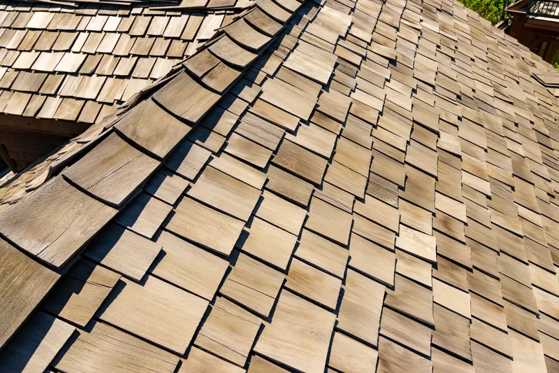 Close view of a weathered cedar shake roof with layered hand-split shakes running up to the ridge