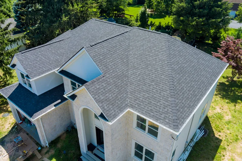 Aerial view of a two-storey house with a new grey architectural shingle roof and dormers