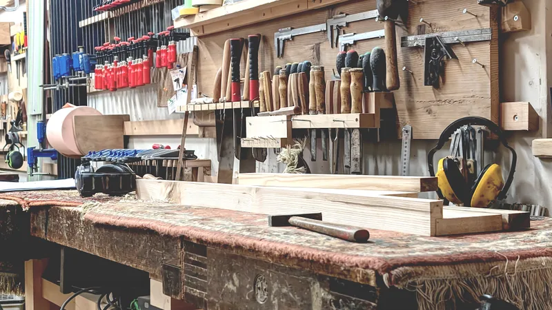 Chisels, planes, clamps and ear defenders hung in rows above a worn workbench in a carpentry shop