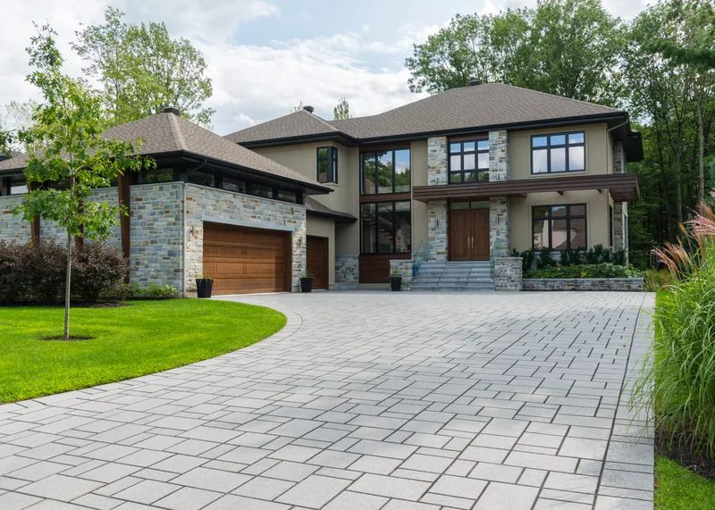 Stone piers, sand-float stucco and white-oak carriage doors across the Briar Hollow arrival court