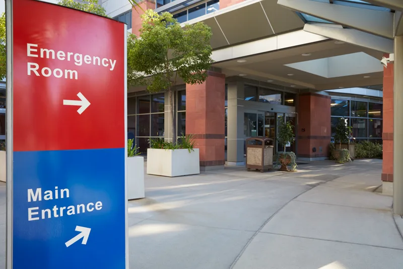 Hospital campus entrance with red emergency room and blue main entrance wayfinding signs