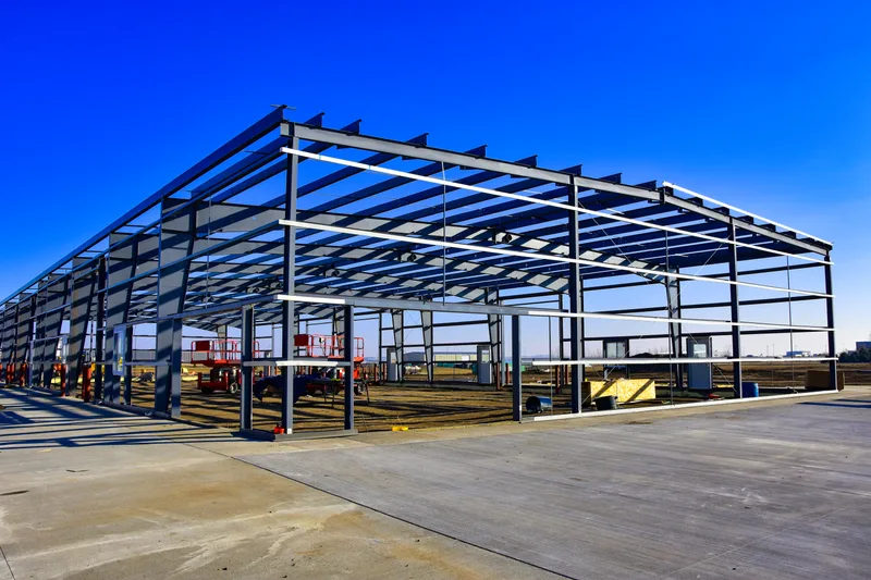 Blue structural steel frame of a new commercial building rising under a clear sky