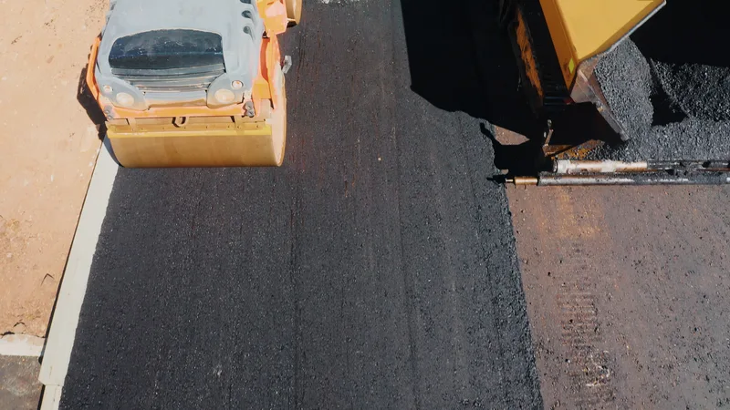 Tandem roller rolling fresh asphalt tight to a curb