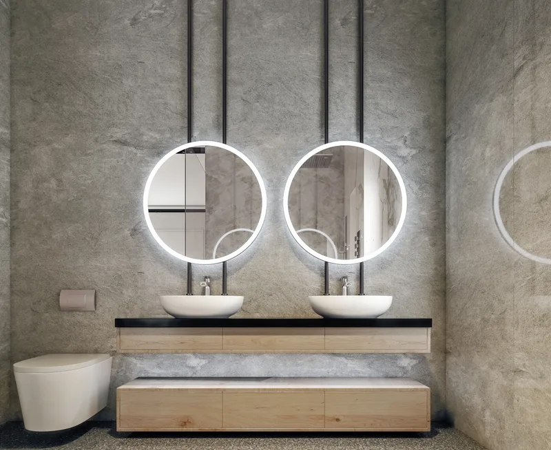 Primary bathroom lined in large stone-look slabs, with a floating double vanity and two round lit mirrors