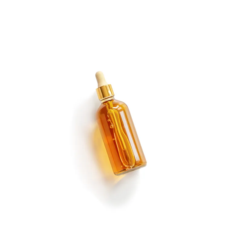 Amber glass dropper bottle of Golden Hour Face Oil lying on a white surface, the golden oil catching the light