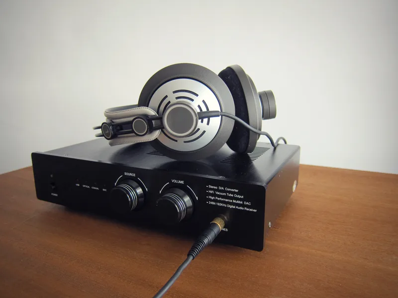 Halvorsen HP-60 open-back headphones resting on a black desktop DAC and amplifier on a wooden desk