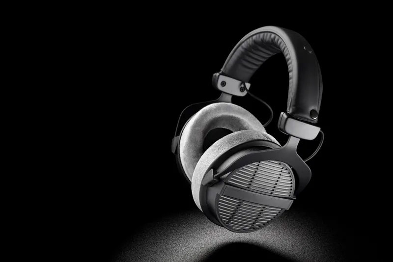 Halvorsen HP-90 open-back headphones with grey velour pads and slotted metal grilles, lit from below against black