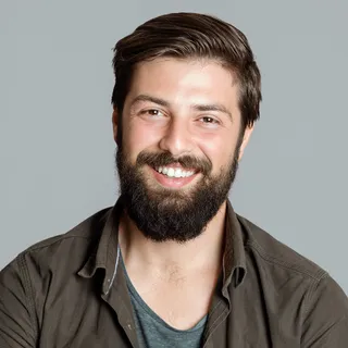 Portrait of Callum Reyes, a smiling bearded man in an olive shirt