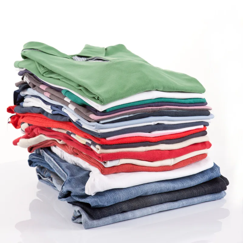 Tall stack of freshly folded tees, polos, and jeans in greens, whites, reds, and blues