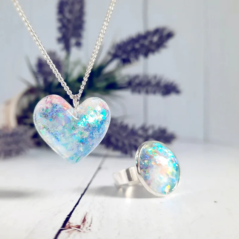 Éa heart-shaped opal pendant on a fine silver chain, its blue and pink fire lit against dried lavender stems