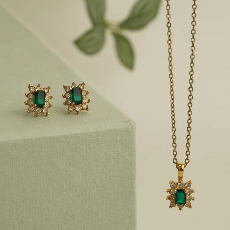The Verte emerald pendant and matching starburst studs in yellow gold on a sage plinth
