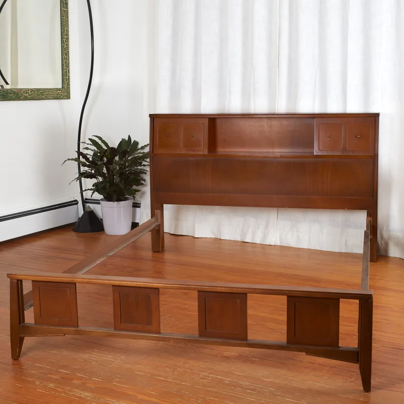 Mid-century walnut bed frame with a storage headboard with sliding compartments, shown in a bright room before the mattress goes on
