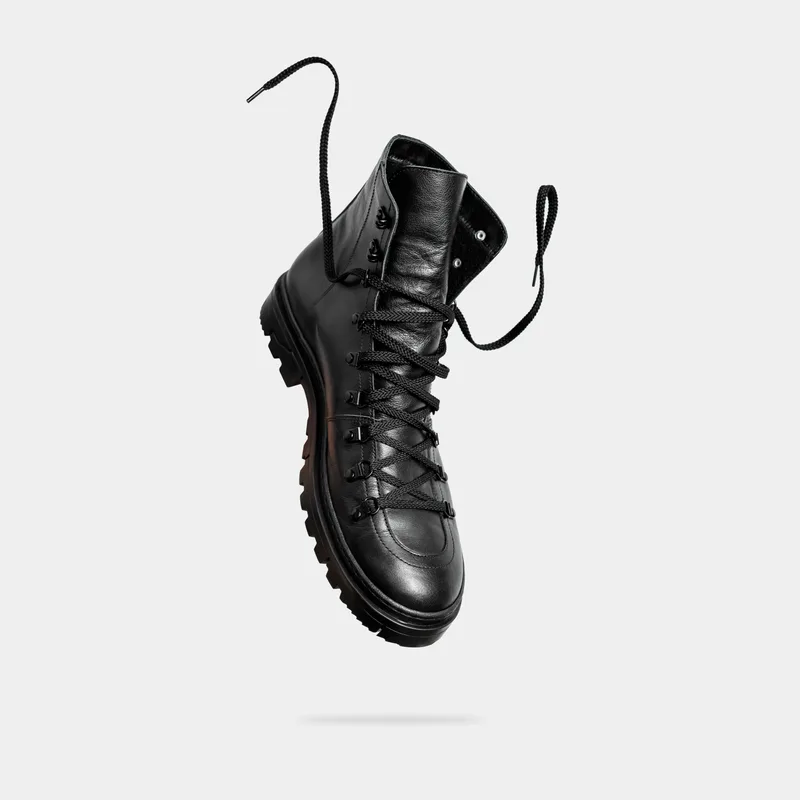 Black leather Scree Runner hiking boot with lugged outsole and speed-hook lacing, floating against a grey studio background