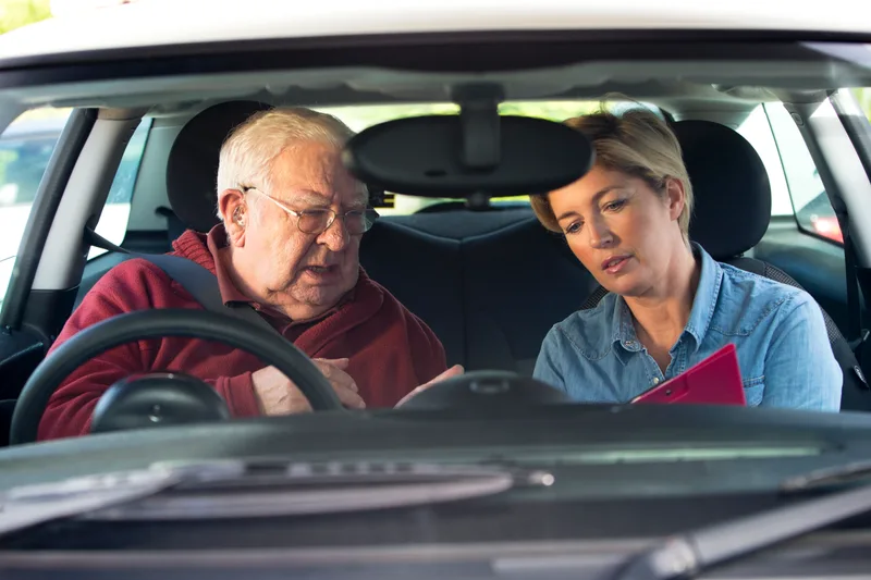 Senior driver talking through lesson notes with his instructor from the driver's seat