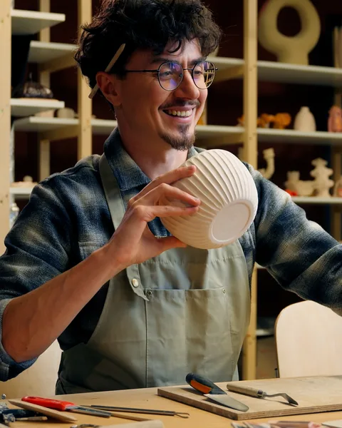 Nico Ferrante, smiling in his studio with a ribbed white bowl in his hands