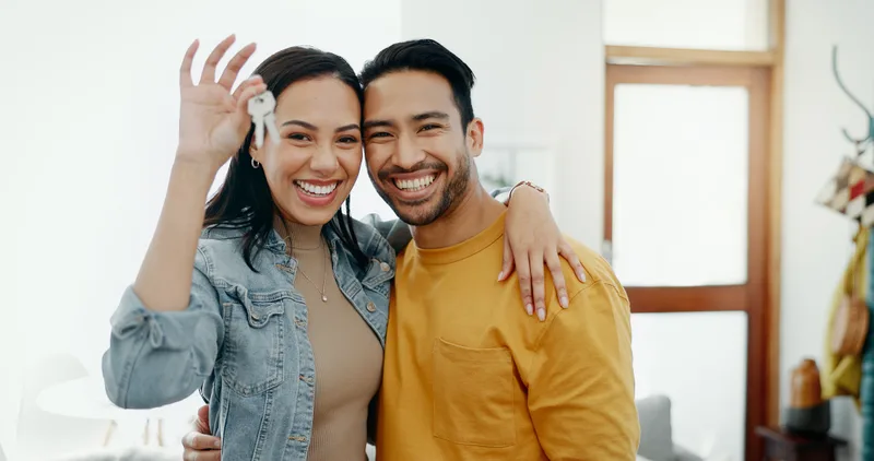 Two smiling small-business owners holding up the keys to their newly leased second location